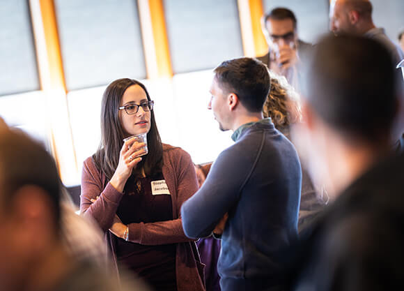 A woman holding a drink and talking to a man in a crowded room
